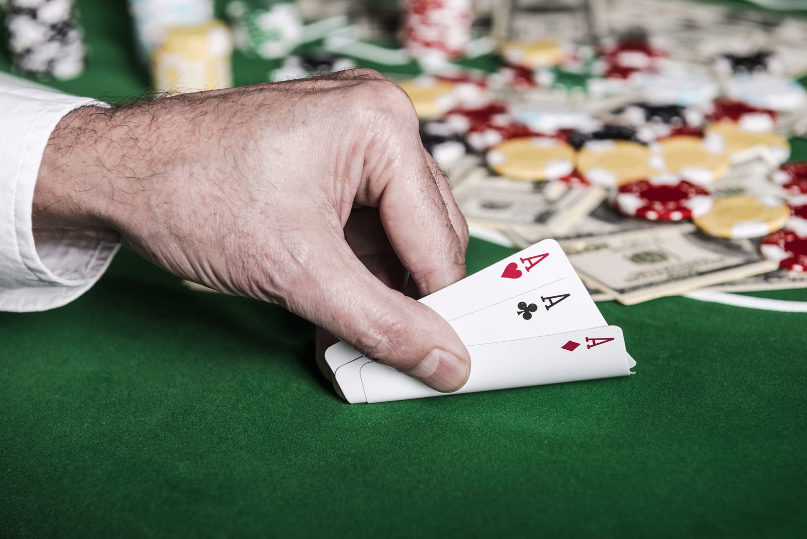 Nice combination. Close-up of male hand showing his cards on the poker table with chips and money laying in the background