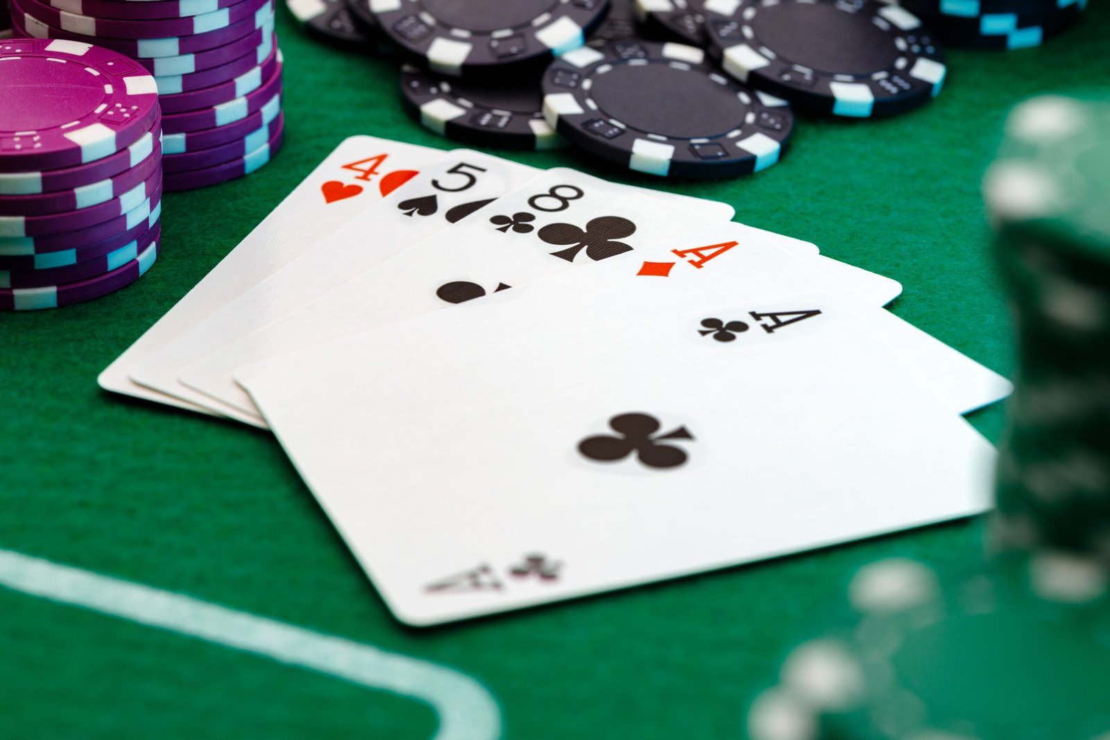 Playing cards and chips on green casino table background close up