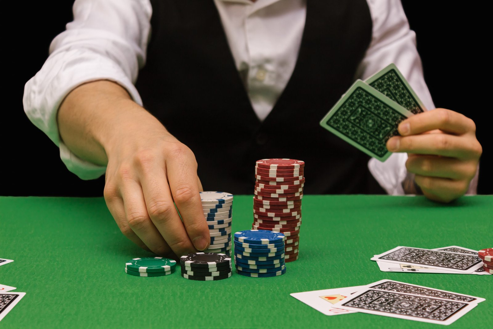 Male professional poker player placing a bet playing the game of poker in a casino with green baize and black. Ruined concept, online winner